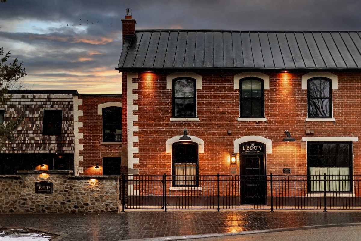 The Liberty Inn in Alton, a red-brick 1855 inn with arched windows and a black iron fence, lit at dusk