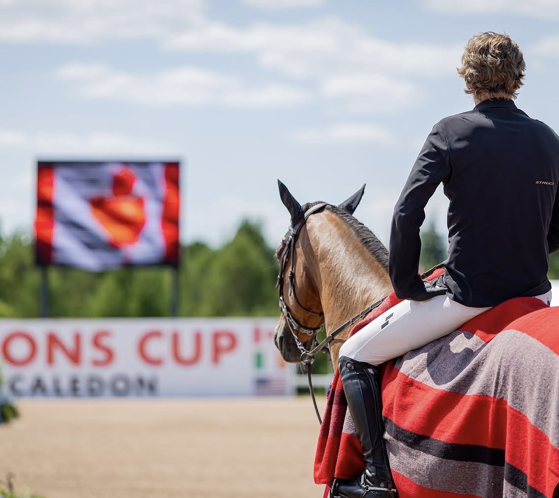 Rider with cooler facing the Nations Cup Caledon banner